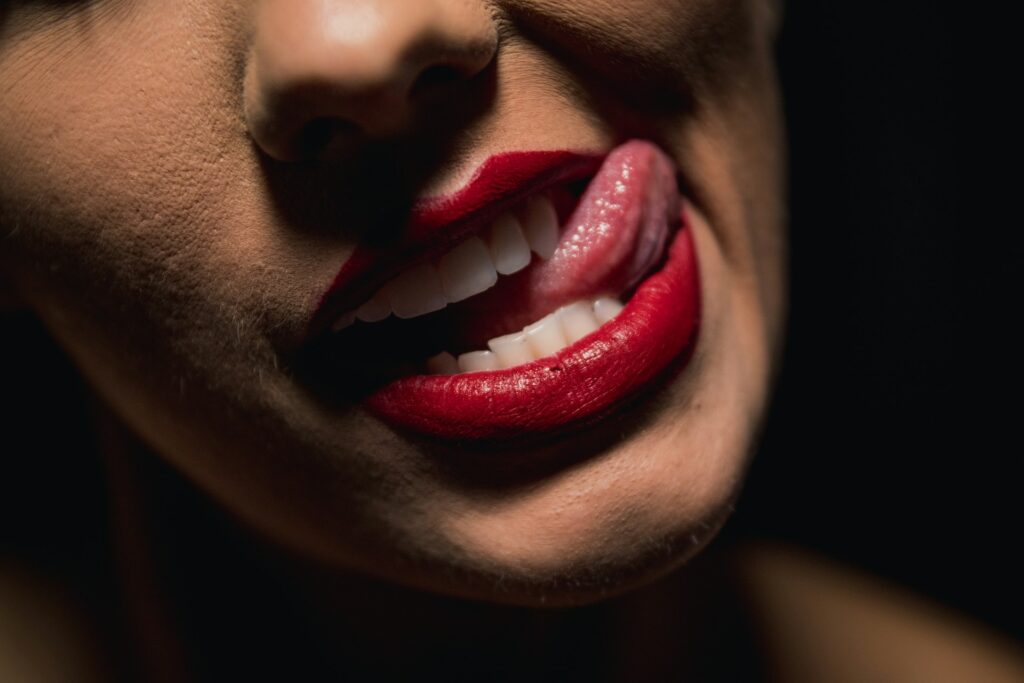 A woman with red lipstick sticking out her tongue.