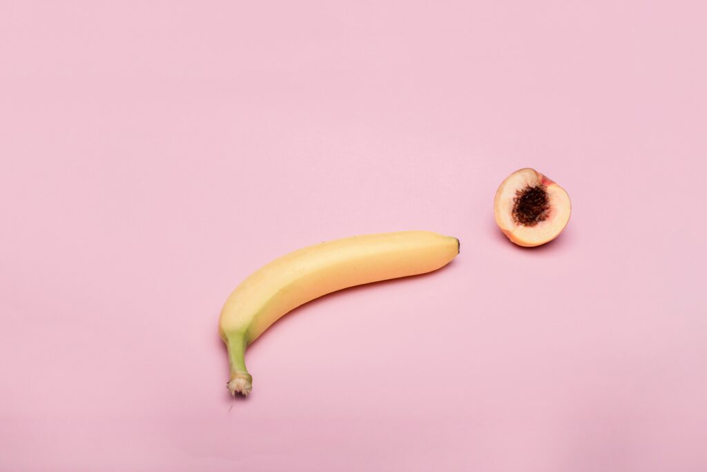 banana and half a peach on a light pink background