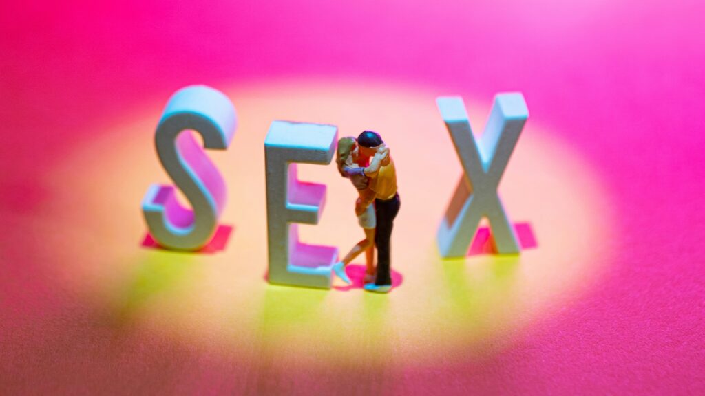 the letters SEX and figuring of couple embracing with pink background