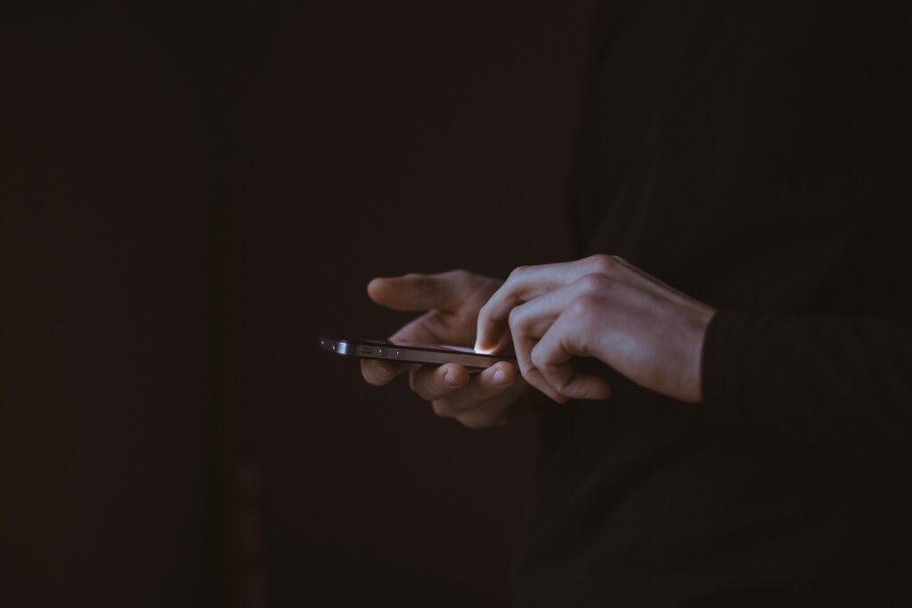 pair of hands texting on a black background