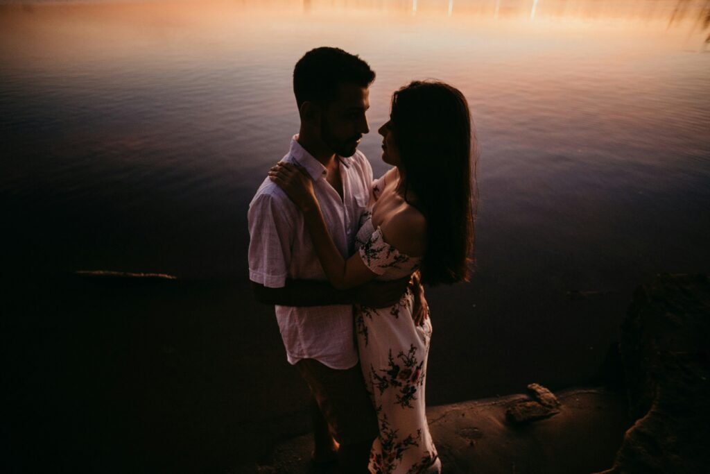man and woman by the water embracing and staring into each others eyes