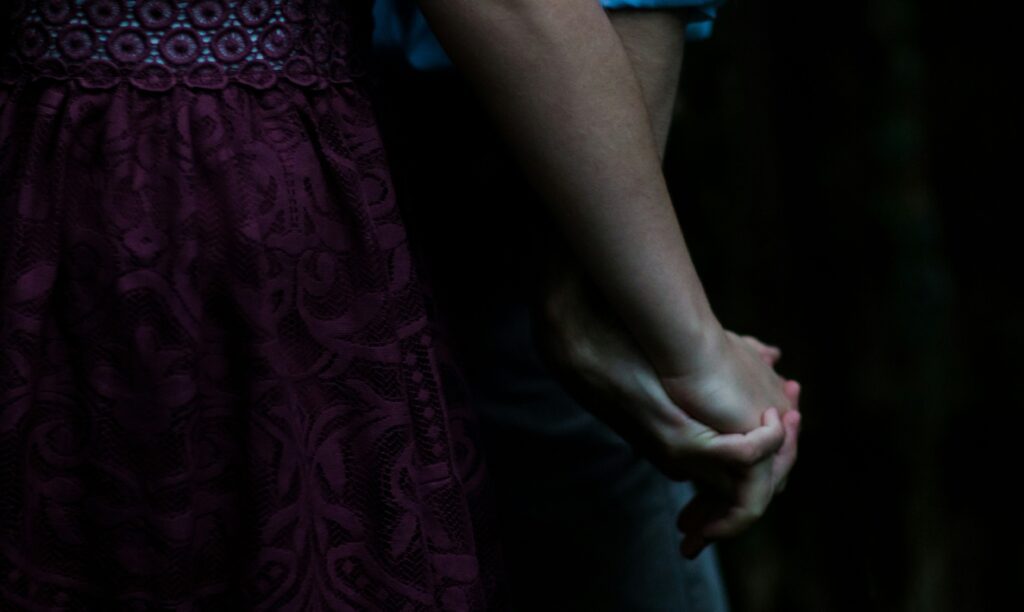 man and woman holding hands with black background