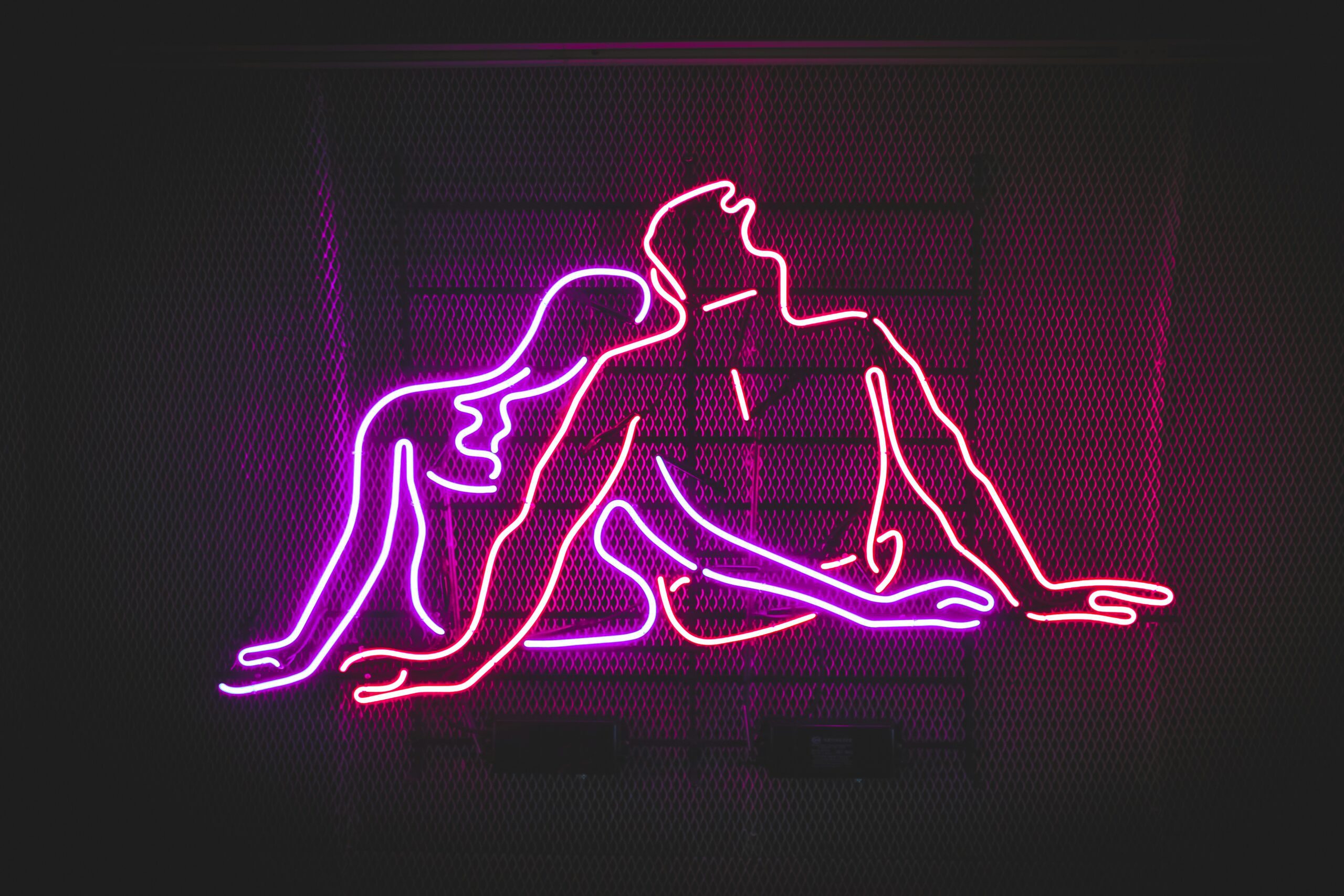 man and woman lined drawing in pink and red neon on black background