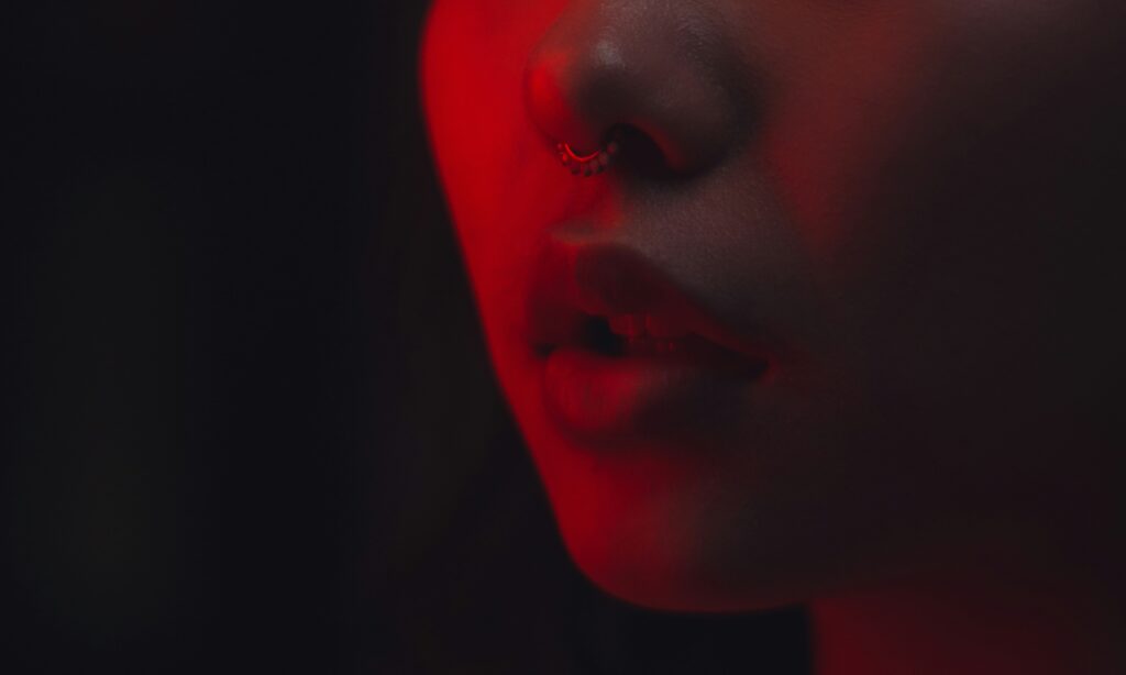 woman’s mouth in red lighting with black background