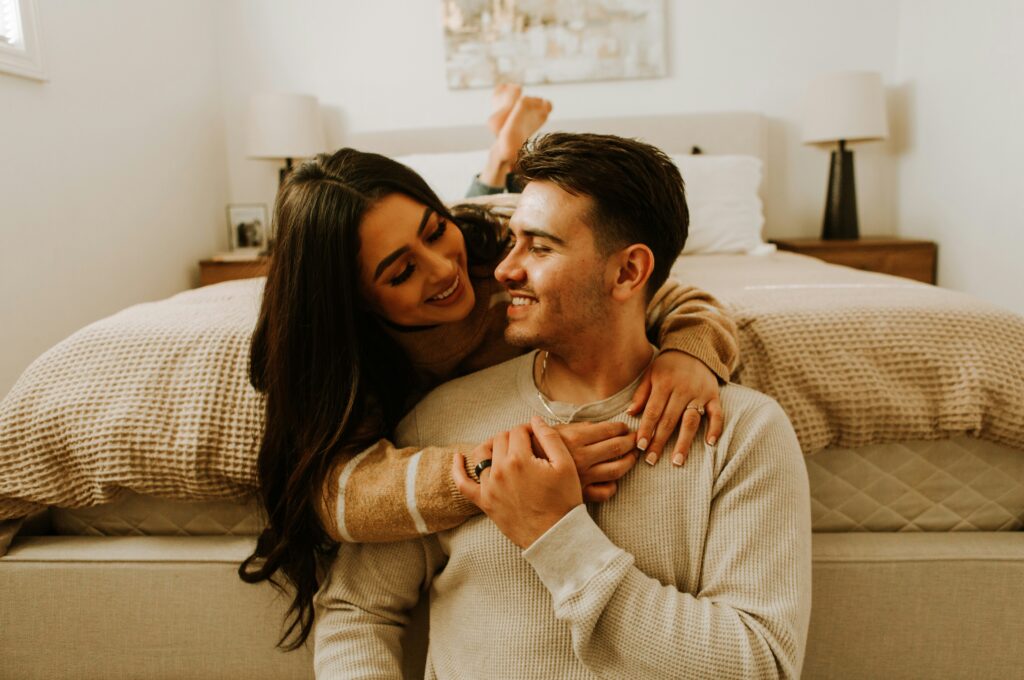 Woman and man hugging near bed