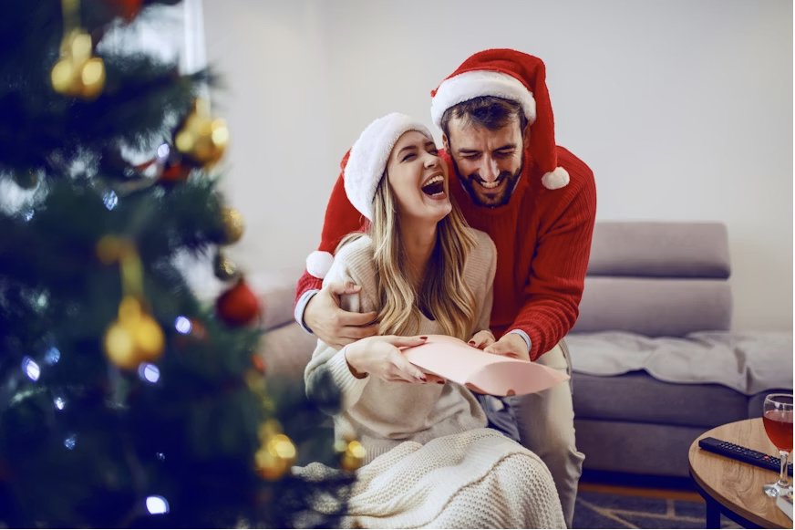 Man and woman laughing next to Christmas tree