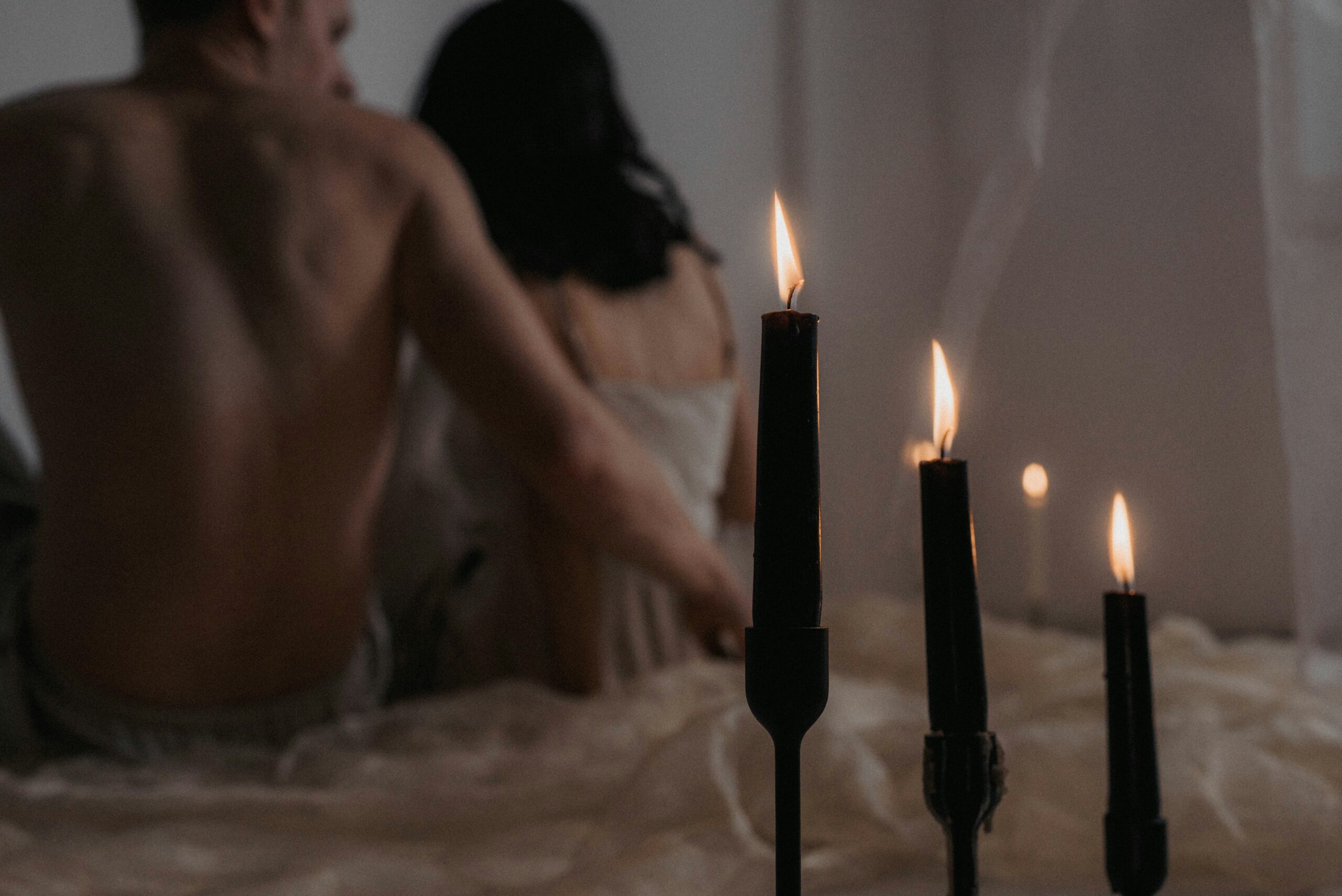 Man and woman sitting in bed next to candles