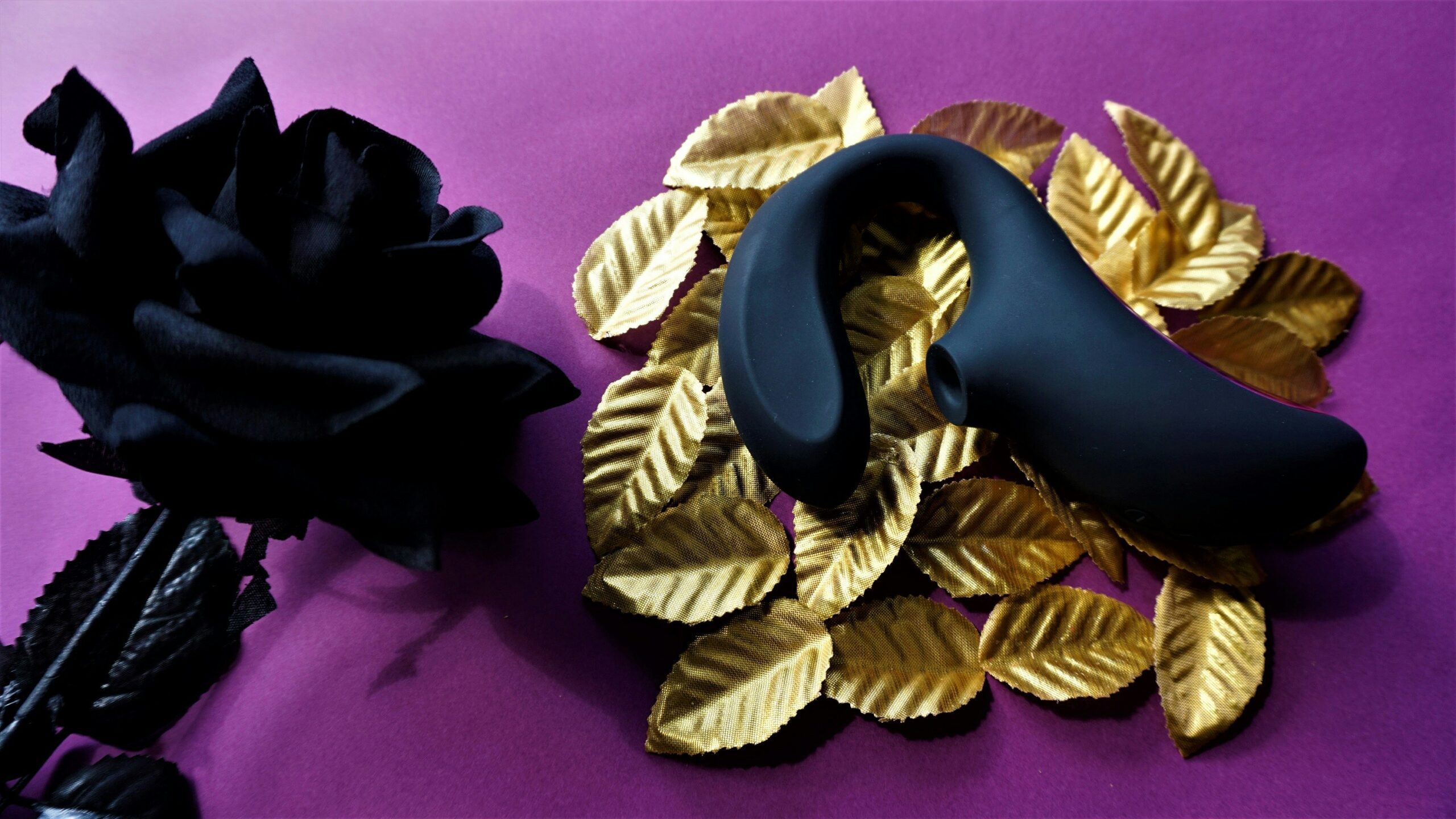 Black sex toy on gold leaves with black rose
