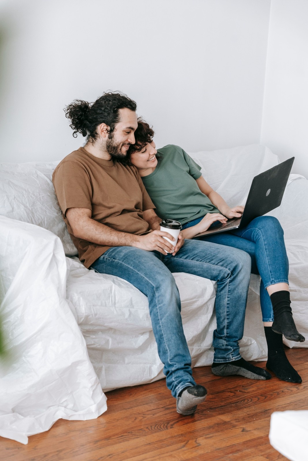 Couple sitting together on a couch browsing a laptop, representing shopping for beginner-friendly toys together