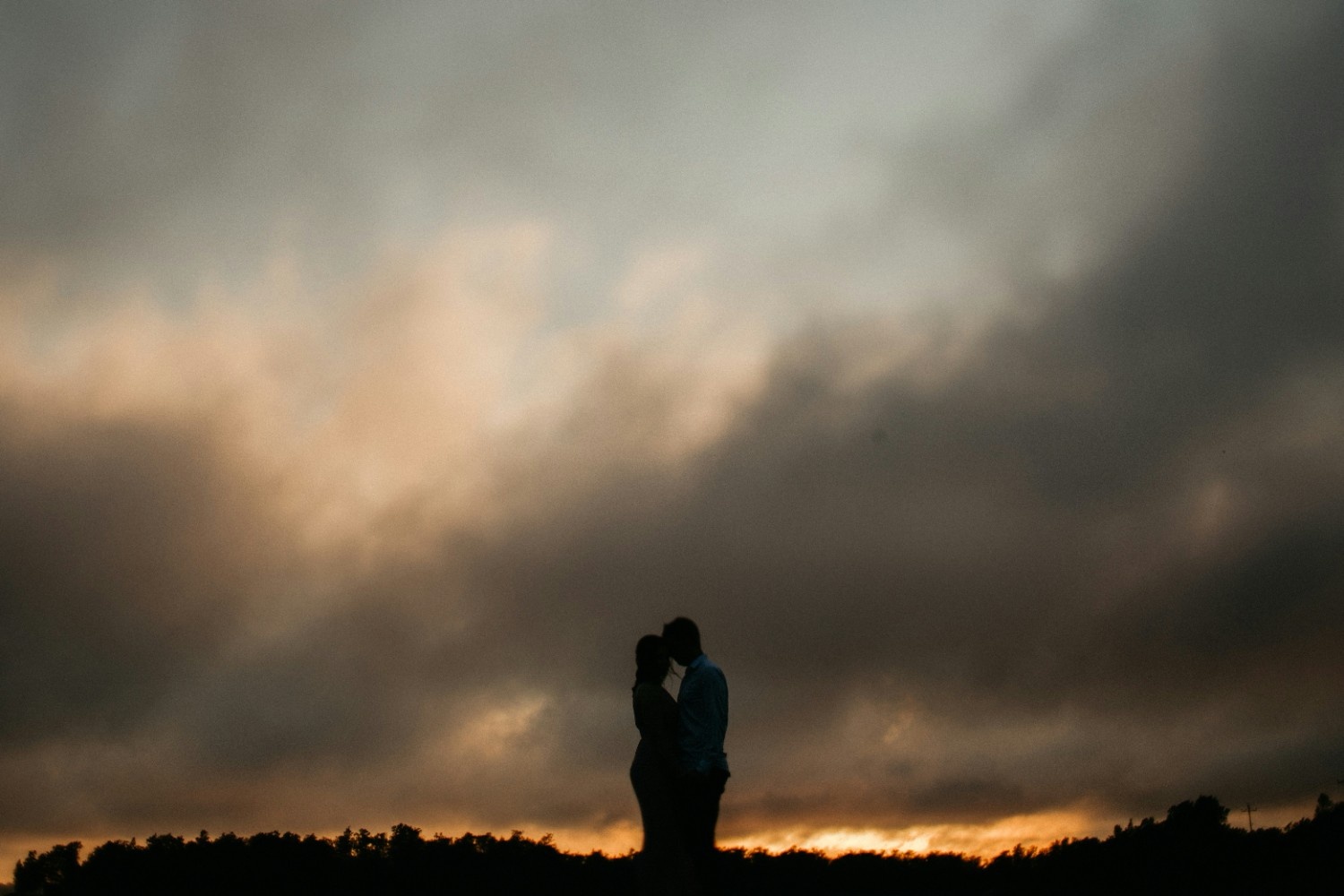 A man and woman standing under a cloudy sky
