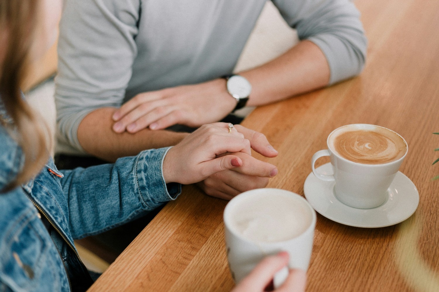 Couple holding hands while talking over coffee