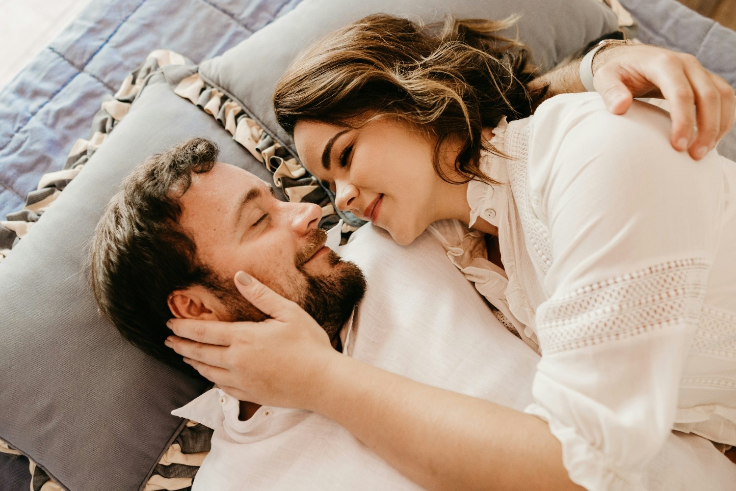 Woman and bearded man in bed embracing