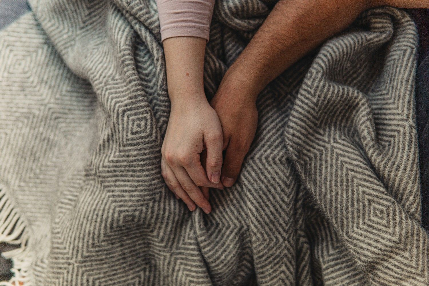 Man and woman holding hands on a blanket